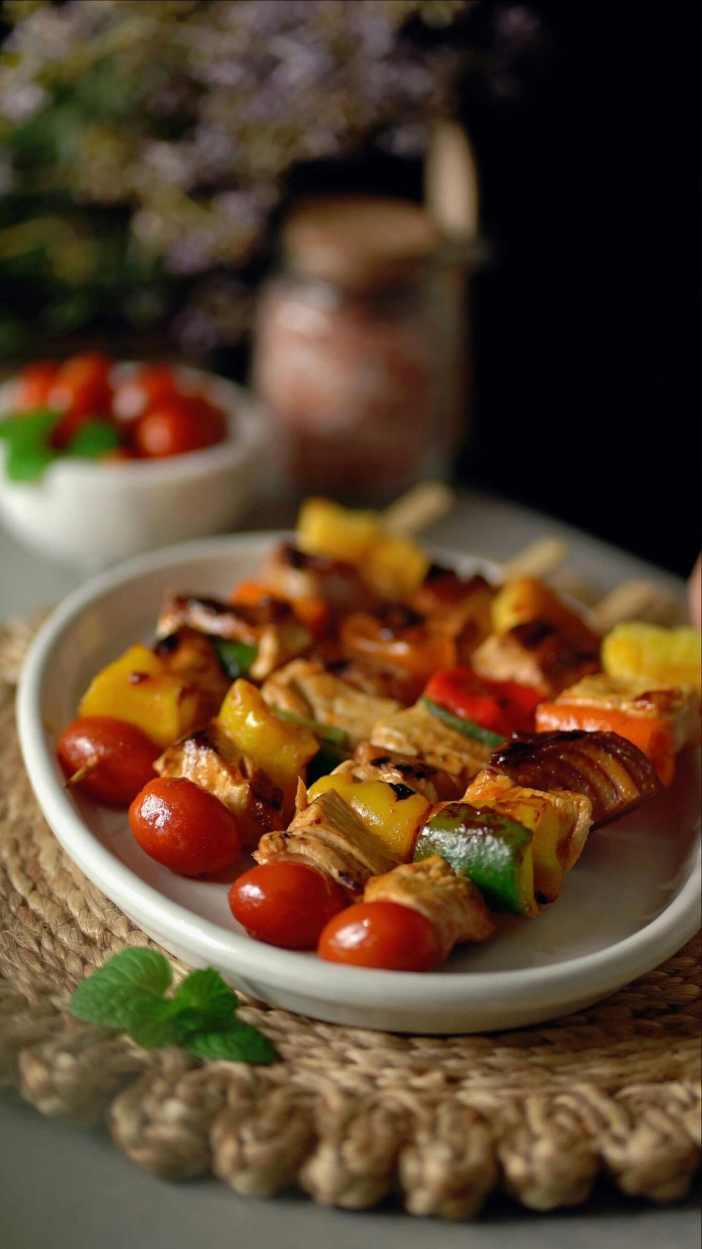 Close-up of colorful grilled chicken and vegetable skewers on a white plate.